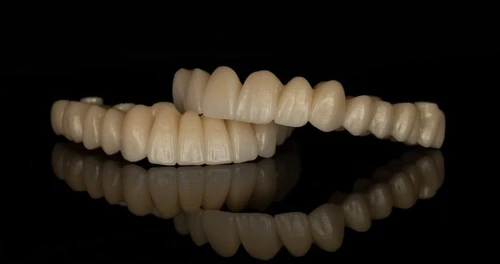 Set of dental crowns or bridges displayed on black reflective surface.